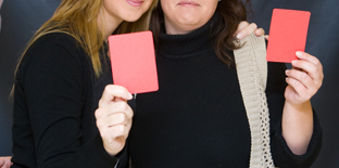 Dos jóvenes muestran tarjetas rojas como rechazo a la violencia de género.