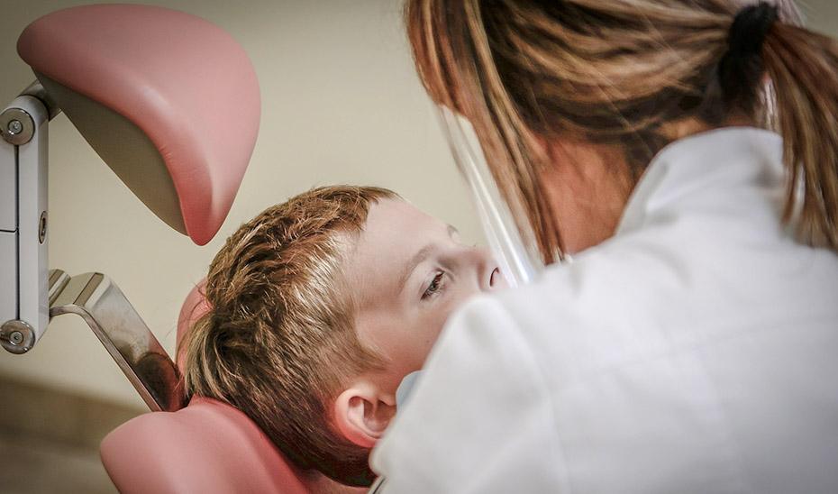 Un adolescente atendido por una profesional en una clínica dental.