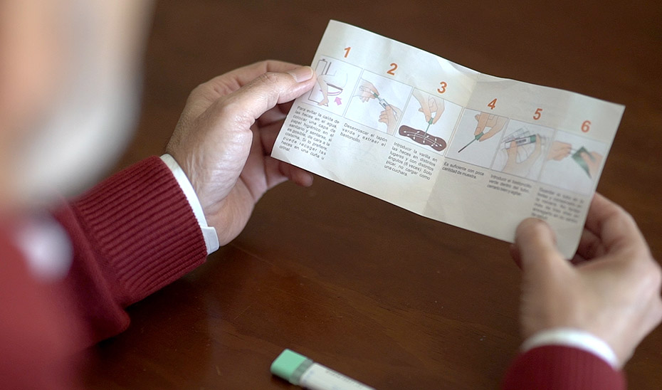 Un hombre lee el folleto con la información sobre el cribado del cáncer de colon.
