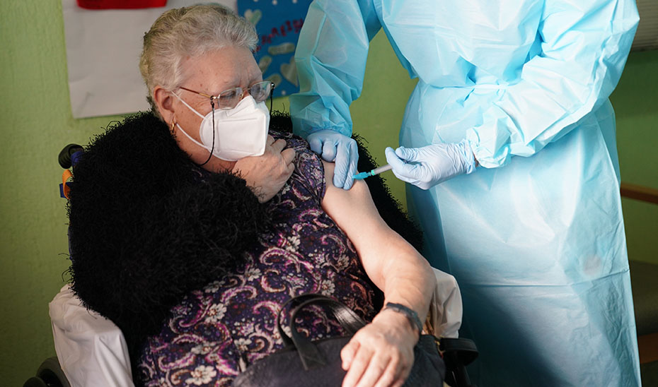 Una enfermera administra la primera dosis de la vacuna a una anciana.