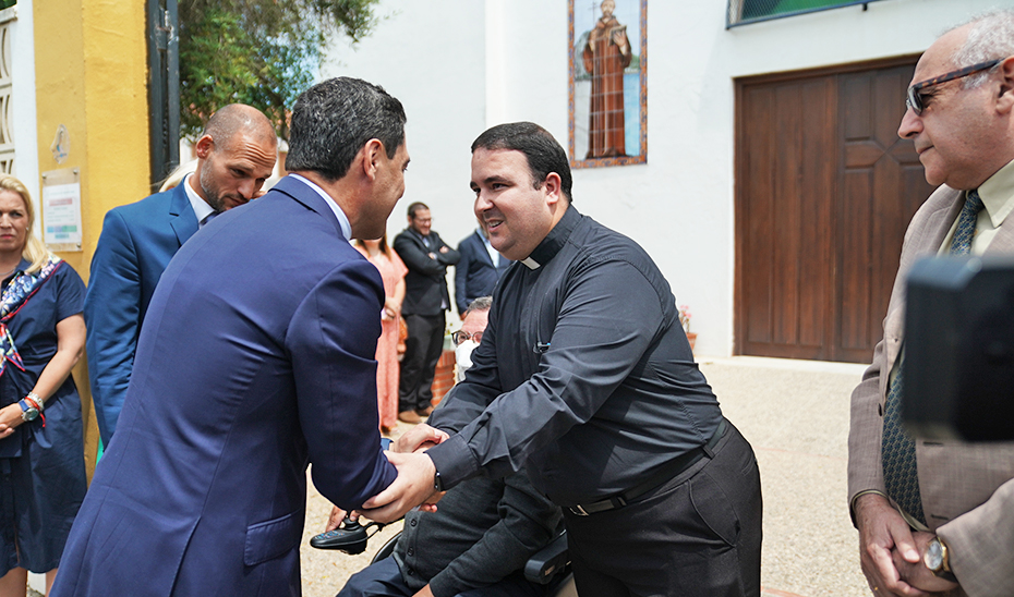 El presidente de la Junta, Juanma Moreno, saluda al párroco de San Bernardo en La Línea.