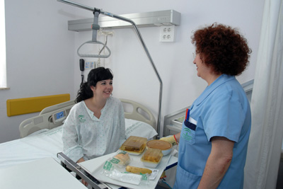 Un profesional del hospital entrega la comida a una paciente