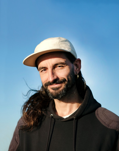 Hombre con gorra, pelo largo y barba en fondo azul