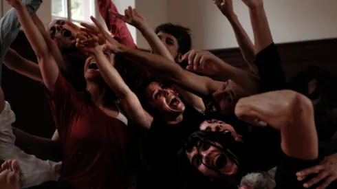 Grupo de personas con las manos levantadas bailando o celebrando algo. Ambiente energético y alegre.