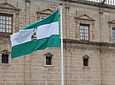  La bandera blanca y verde ondea al viento frente a la puerta principal
          del Parlamento de Andalucía, durante el acto de homenaje a la insignia.
          