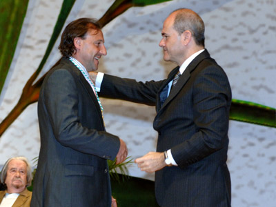 El deportista Fermín Cacho saluda al presidente de la Junta, Manuel Chaves, tras recibir la Medalla de Andalucía, ante la atenta mirada de sus compañeros homenajeados.