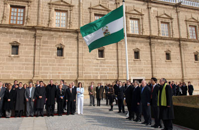 Gobierno andaluz, parlamentarios de la Cámara autonómica, ex presidentes de la Junta y del Parlamento, y otras autoridades invitadas, escuchan el himno de Andalucía tras la tradicional izada de la bandera.