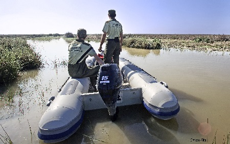Dos agentes de medio ambiente en una lancha motora, supervisando la zona, en un río