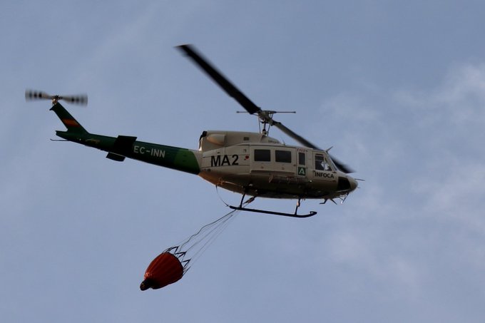 Ampliar imagen: helicóptero del dispositivo INFOCA transportando agua para sofocar un incendio forestal