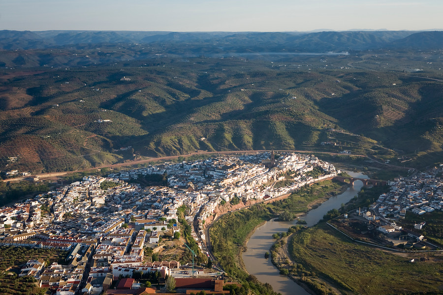 Ampliar imagen: pueblo de Montoro, de casa blancas a la izquierda y río Guadalquivir pasando por la derecha del pueblo, rodeado de montañas verdes
