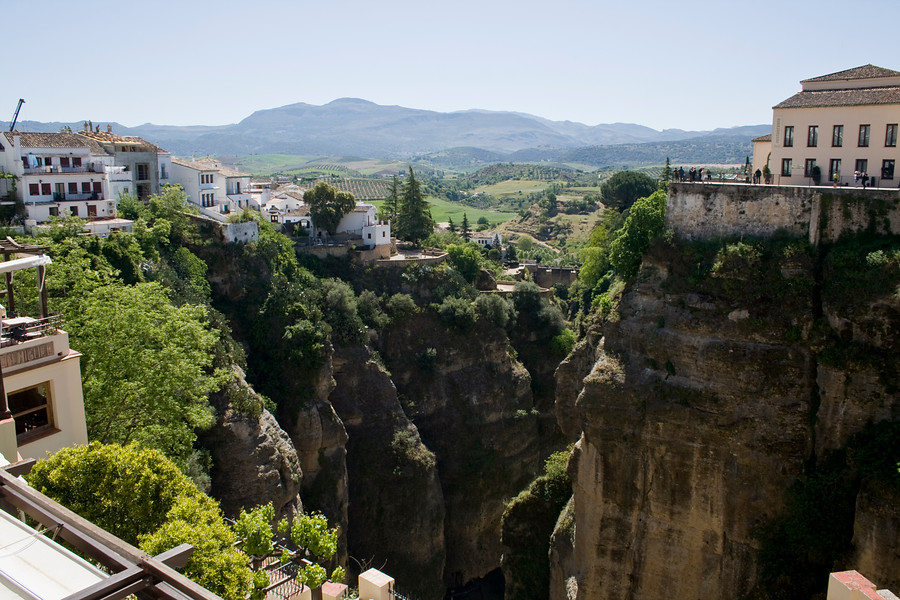 Ampliar imagen: enorme garganta ubicada en Ronda, con vegetación y casas blancas con tradicionales tejados con tejas a ambos lados