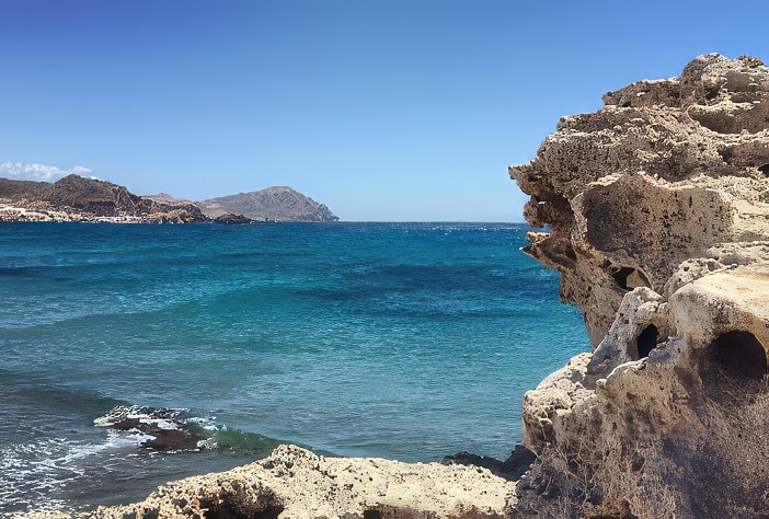 Vista del mar en calma desde un acantilado con formaciones rocosas, en un día soleado