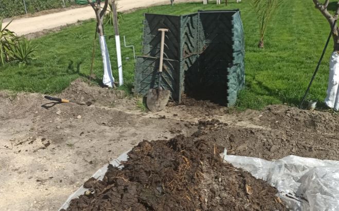 Saco de compost en un huerto y aperos de labranza