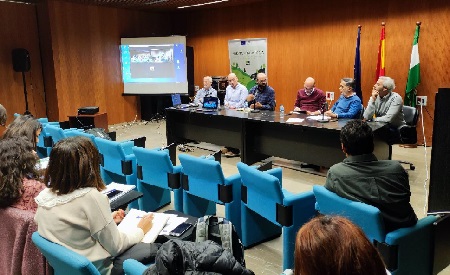 Taller de formación. Sala con proyector y mesa en la que están seis ponente. En frente está el público que asiste