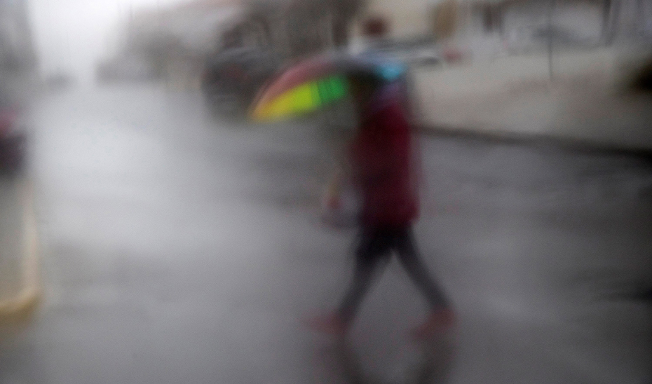 Una persona se resguarda de la lluvia. Foto: EFE.