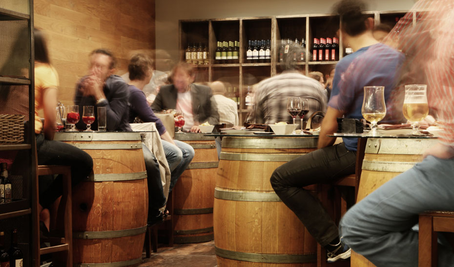 Clientes disfrutando de unas copas de vino en un bar.