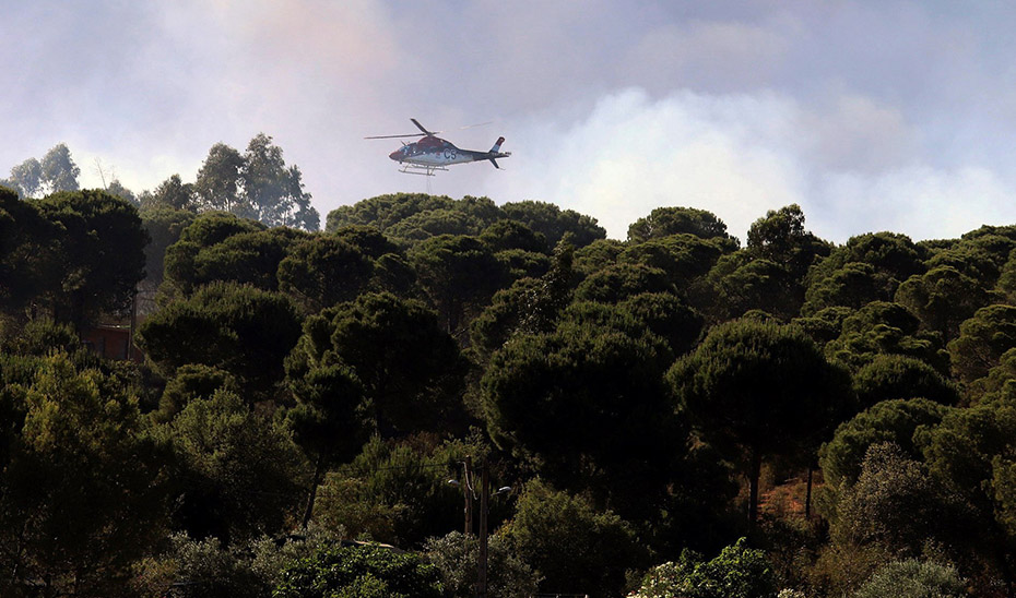 Un helicóptero contraincendios trata de sofocar un fuego declarado en un espacio forestal.