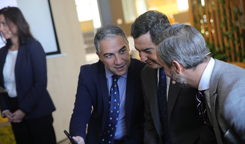 El presidente Juanma Moreno comprueba, con Elías Bendodo y Juan Bravo, el funcionamiento de la app.