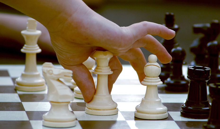 Un niño mueve una pieza sobre un tablero de ajedrez.