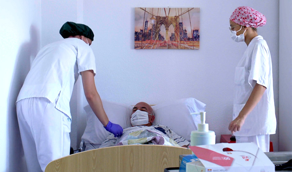 Dos trabajadoras de una residencia de mayores atienden a una persona enferma.