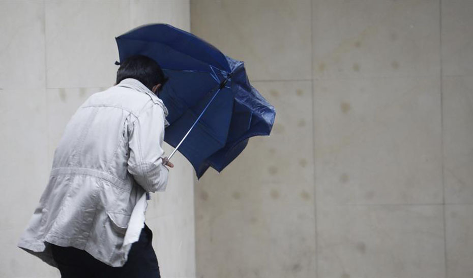 Un hombre se protege con un paraguas de la lluvia y el viento (Agencia EFE).