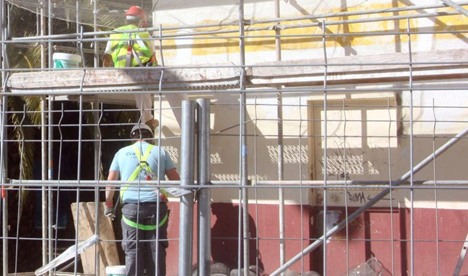 Una pareja de albañiles trabajando entre andamios.