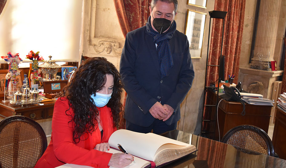 La consejera de Igualdad firma en el Libro de Honor del Ayuntamiento de Sevilla en presencia del alcalde.