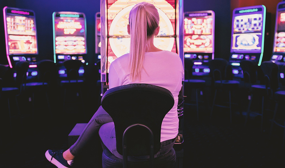 Una joven juega con una máquina tragaperras en un salón de juegos.