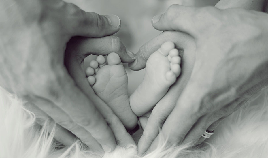 Unos padres acarician los pies de su bebé.