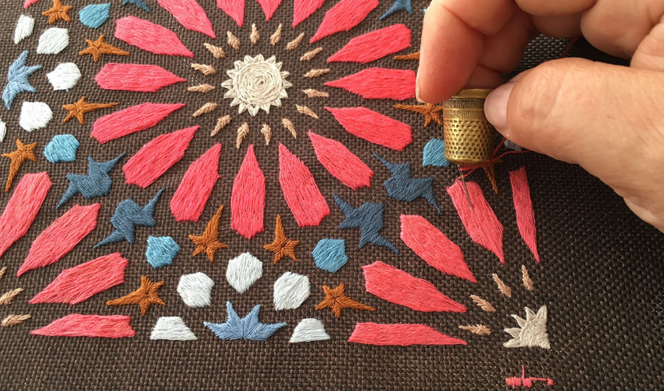 Una bordadora realiza un trabajo artesano inspirado en la azulejería tradicional andaluza.