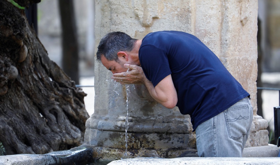 Un hombre bebe agua de una fuente en Córdoba
