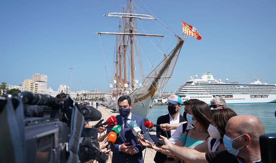 El presidente Juanma Moreno atiende a los medios ante el Juan Sebastián Elcano, atracado en el puerto de Cádiz.
