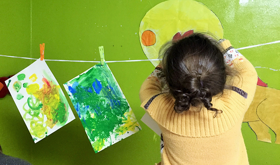 Una niña cuelga sus pinturas para que se sequen en una casa de acogida para víctimas de violencia de género.