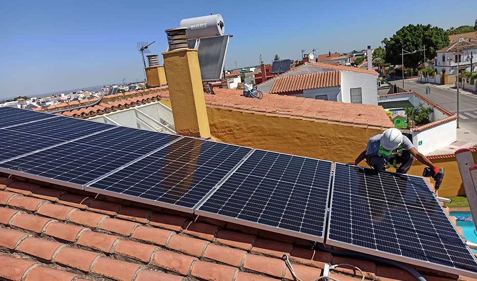 Un trabajador coloca placas fotovoltaicas para autoconsumo en una vivienda.