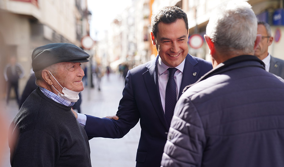El presidente de la Junta, Juanma Moreno, saluda a vecinos de Lucena al pasear por la calle.