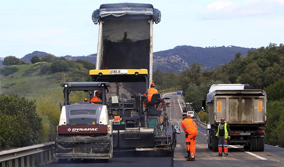 Operarios trabajando en unas obras de reparación del firme en una carretera autonómica.