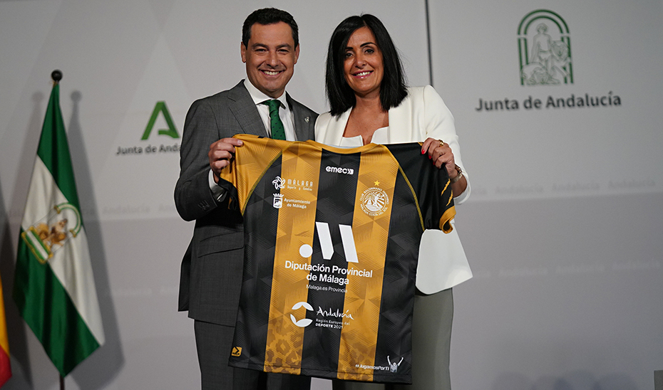 Juanma Moreno recibe una camiseta del Málaga Costa del Sol de manos de la presidenta del club, María José Moreno.