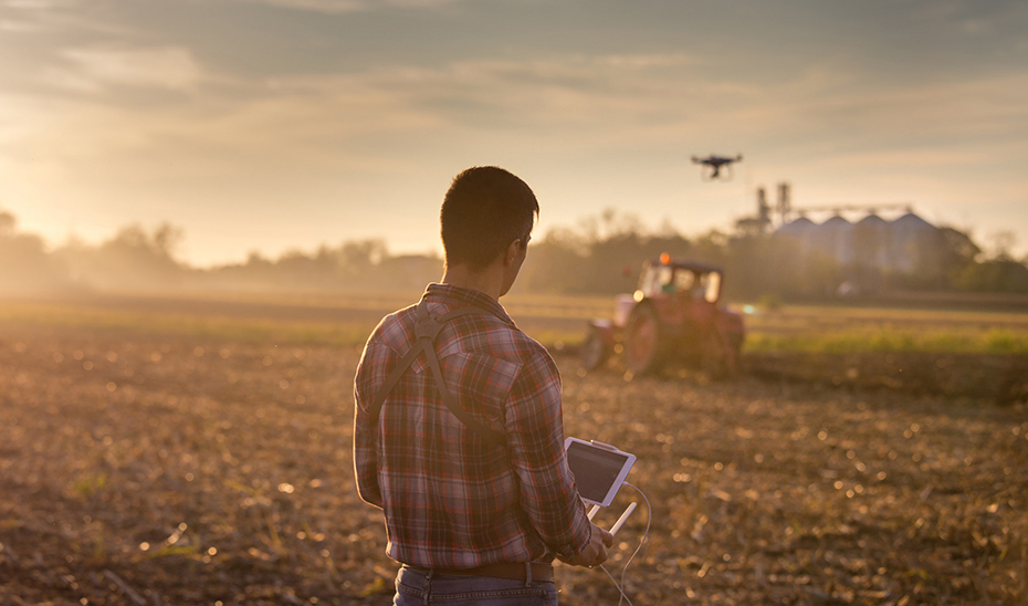 Un joven agricultor valiéndose de las nuevas tecnologías para desarrollar su labor en el campo.