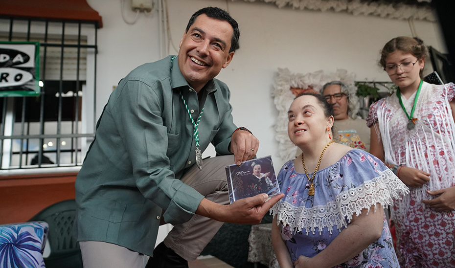 El presidente Juanma Moreno recibe de una joven cantante el disco que acaba de grabar, durante su visita al Rocío.