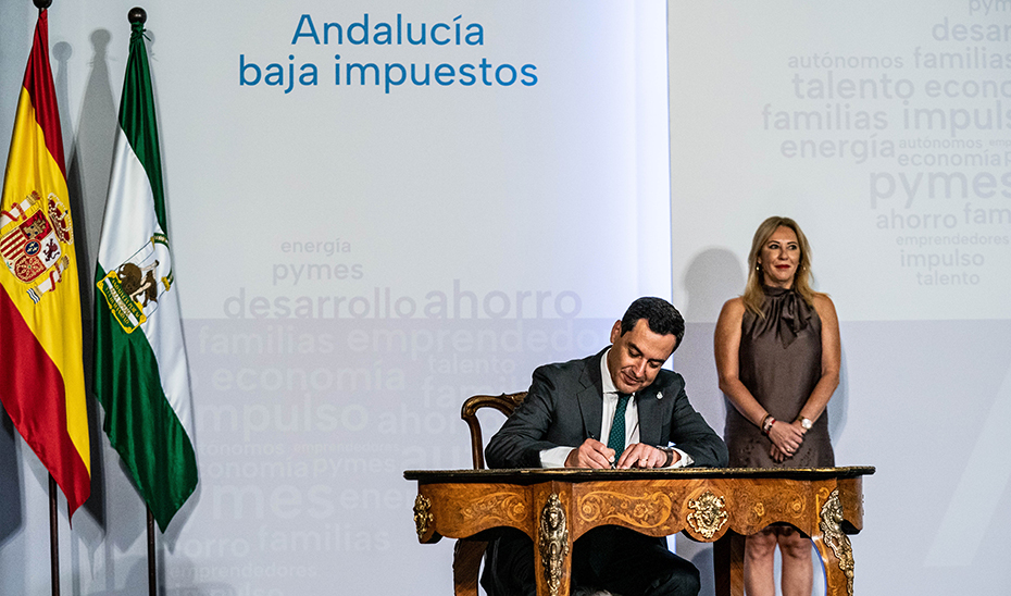 Juanma Moreno, en presencia de Carolina España, en el momento de la firma de la nueva normativa en materia fiscal de Andalucía.