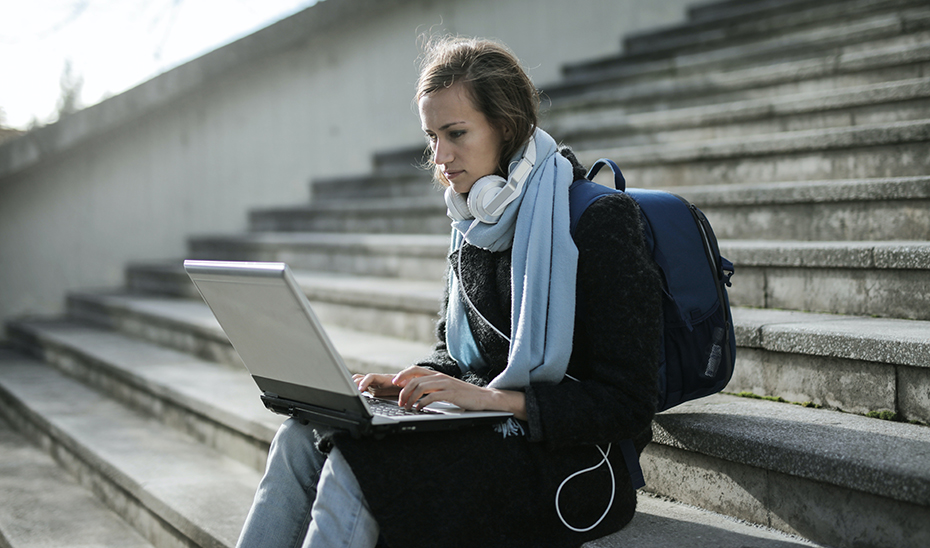 Una estudiante extranjera repasa apuntes en su portátil.