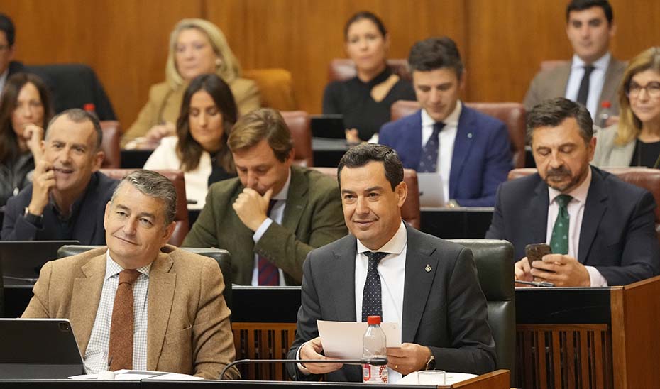 El presidente de la Junta, Juanma Moreno, y el consejero de la Presidencia, Antonio Sanz, (a la izquierda) en un momento del Pleno del Parlamento andaluz.