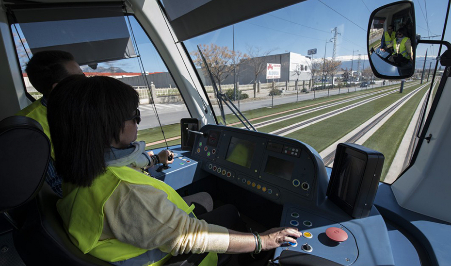 Una conductora conduce uno de los convoyes del Metropolitano de Granada en un tramo al aire libre.