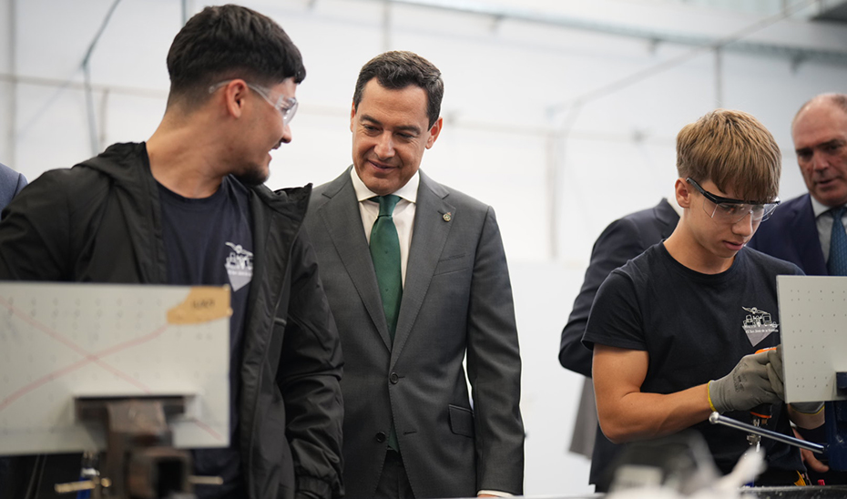 Dos alumnos de las nuevas instalaciones explican su actividad a Juanma Moreno.