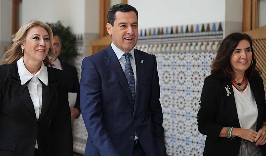 Moreno, acompañado de las consejeras de Economía, Carolina España, y de Empleo, Rocío Blanco, en los pasillos del Parlamento de Andalucía.