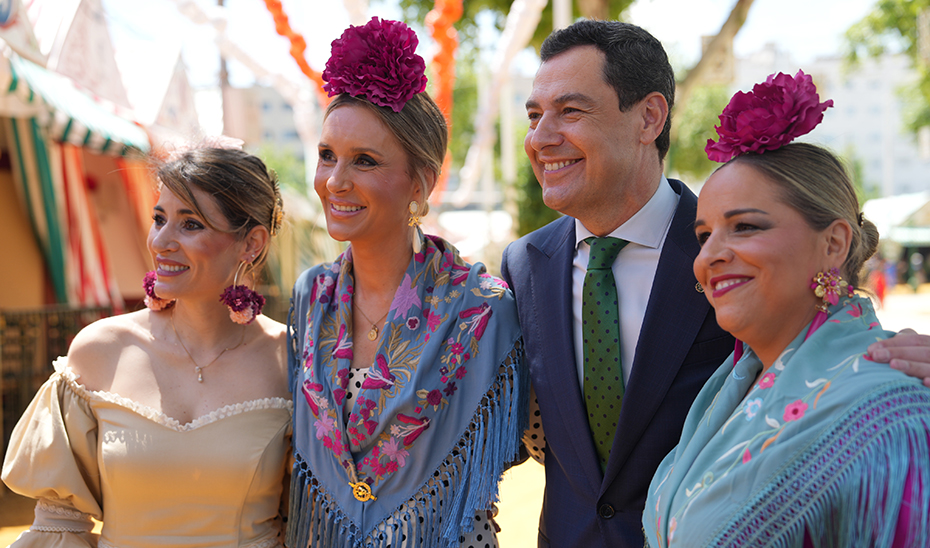 Juanma Moreno posa con varias mujeres vestidas de flamenca en la Feria de Sevilla.
