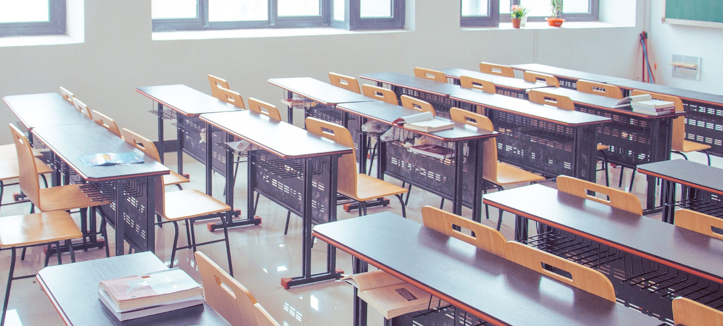 Un aula con varios pupitres, mesas y libros